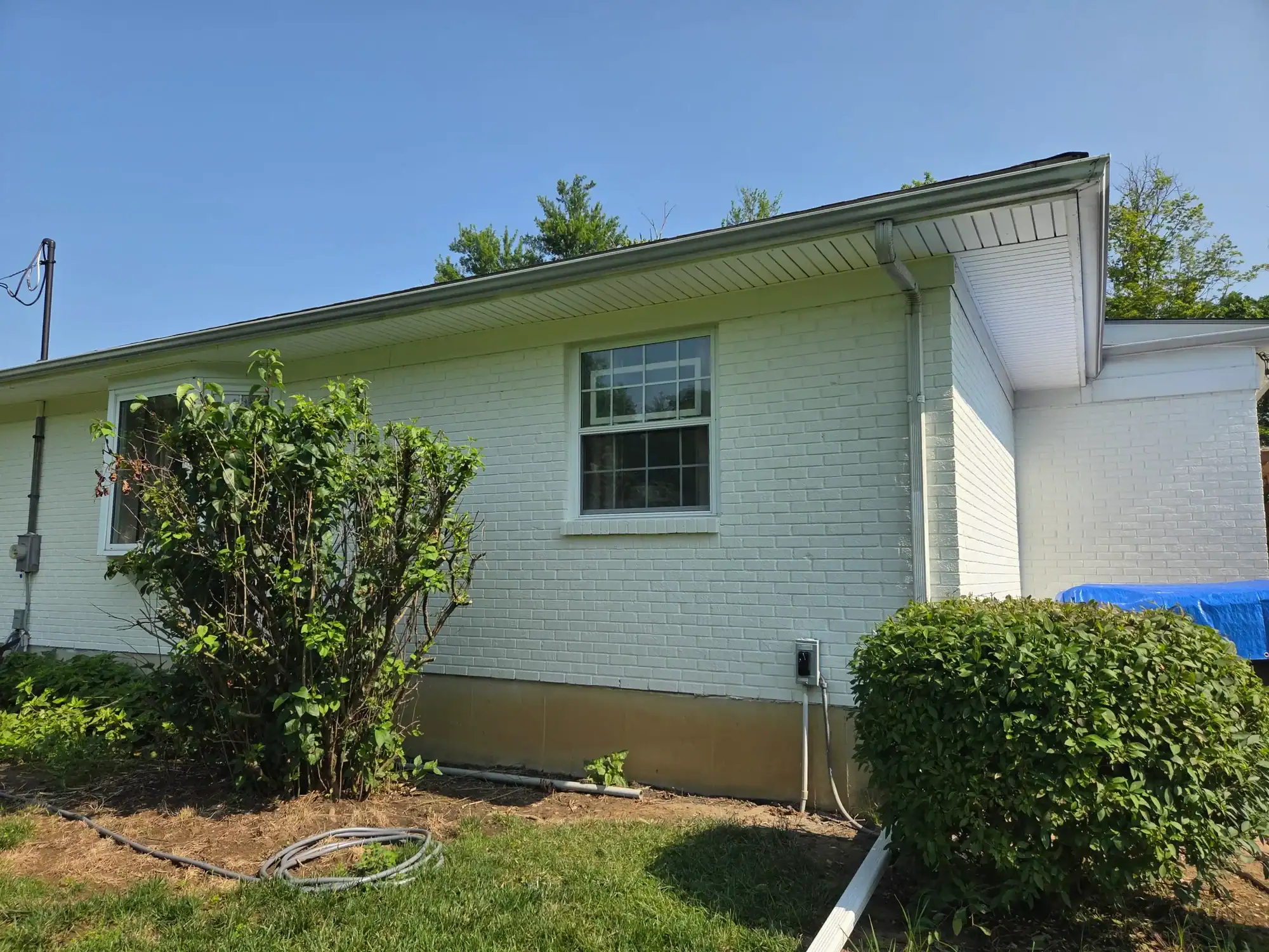 Professional exterior house painting Cincinnati - mint green painted brick home with white trim and landscaping